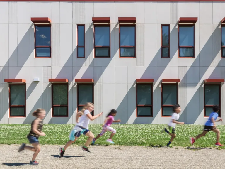 Children running against the facade of the Columbus Spanish Immersion Academy