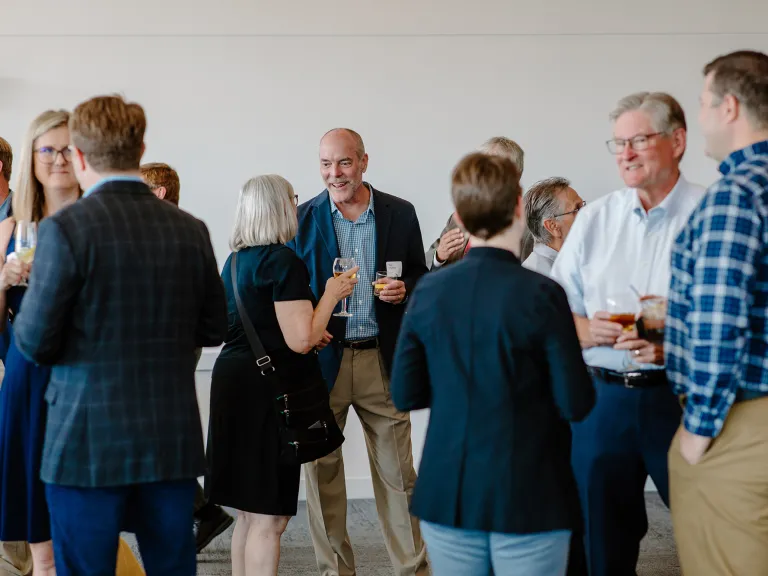 Group of people standing and talking at the DesignGroup 50th anniversary event.