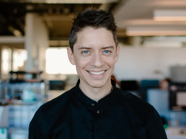 Daniel Mathur smiling, wearing a black button down shirt