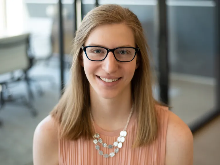 Emily Wagner smiling, wearing a pink blouse and statement necklace