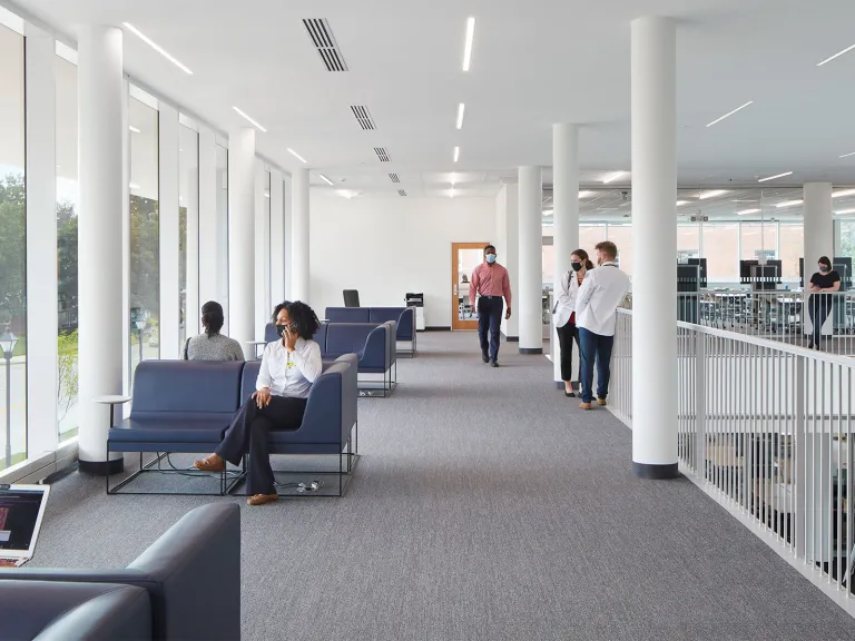 People in a brightly and natural lit waiting area in a medical facility.