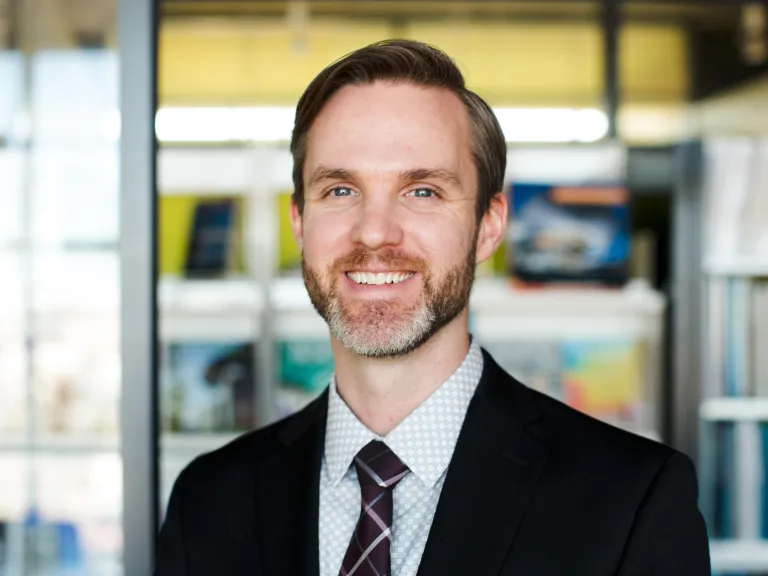 Jeff McCambridge smiling, wearing a black blazer and tie