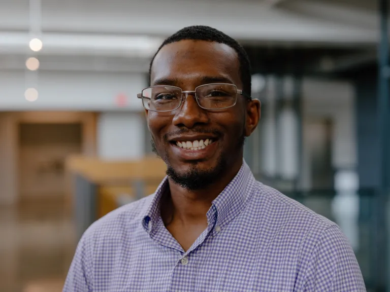 Kemet Floyd smiling, wearing a light purple button down shirt