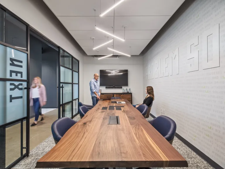 Modern conference room with long wooden table and unique bar ceiling lights