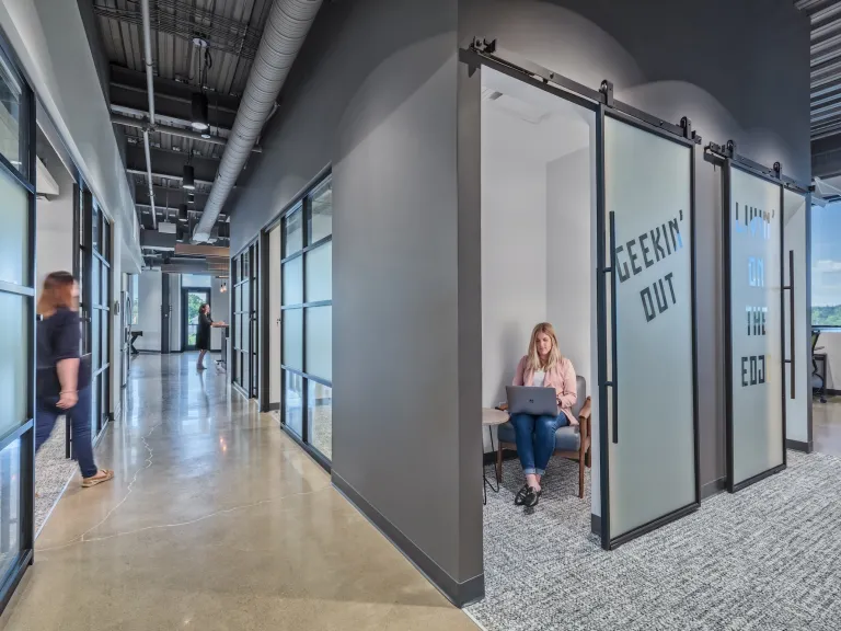 Hallway space featuring several private huddle or phone rooms with frosted glass doors