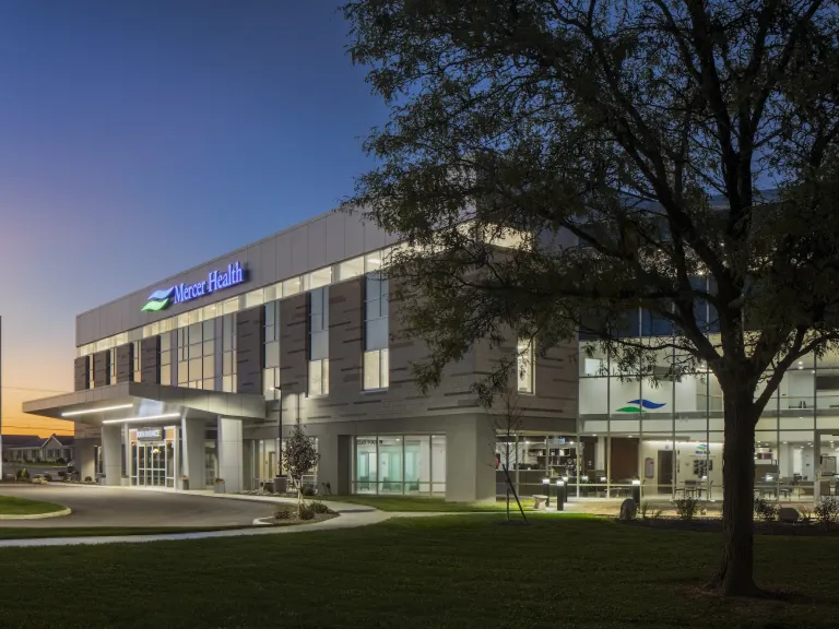 Exterior of Mercer Health in the evening, a modern building with mixed bricks and floor to ceiling windows, multi story building