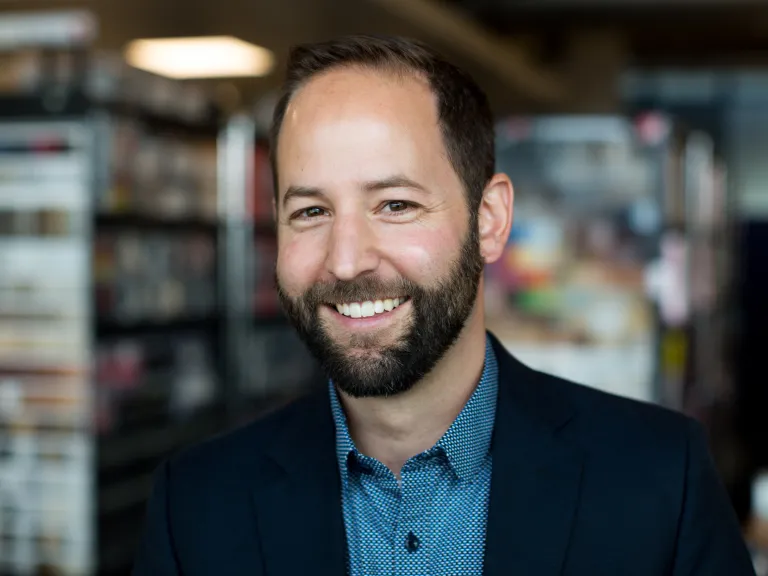 Mike Forejt smiling while wearing a dark navy blazer and teal shirt