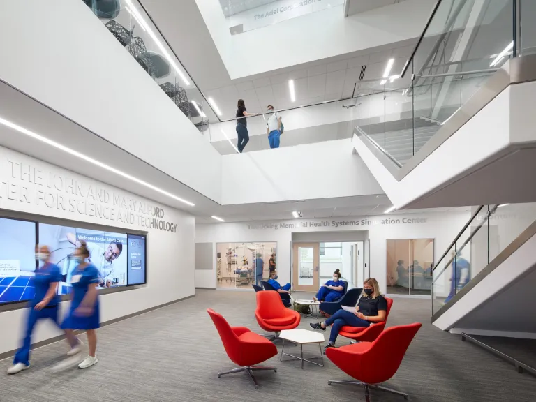 Ground floor lobby space of Alford with dark orange chairs and modern white walls and staircases.