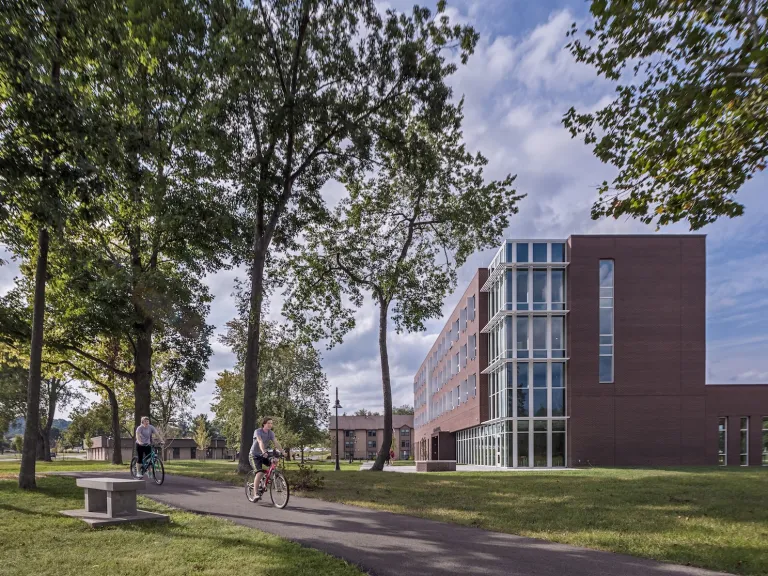 Exterior landscape of McConnell Residence Hall while two student ride past the building on their bikes