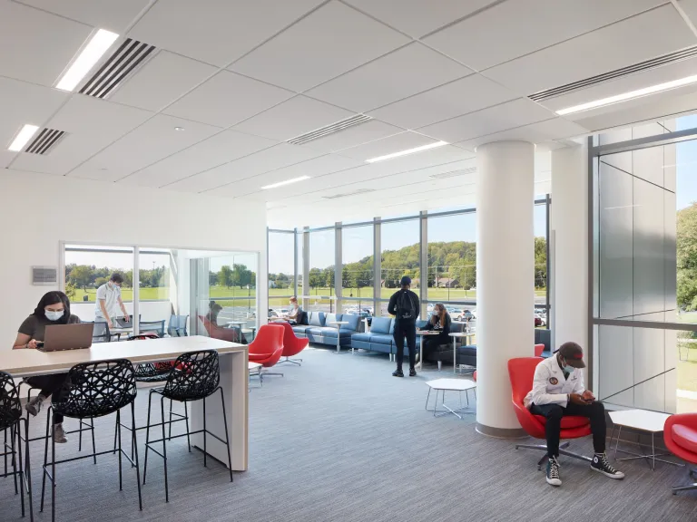 Student lounge in Alford, large floor to ceiling windows of greenspace outside and variety of study tables and couches inside.