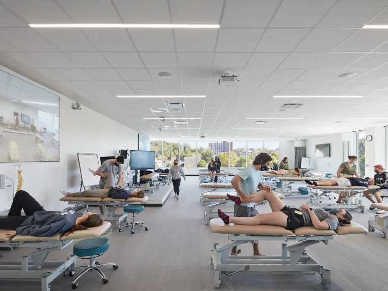 Interior of a class room featuring student volunteering laying on tables and have their legs tested