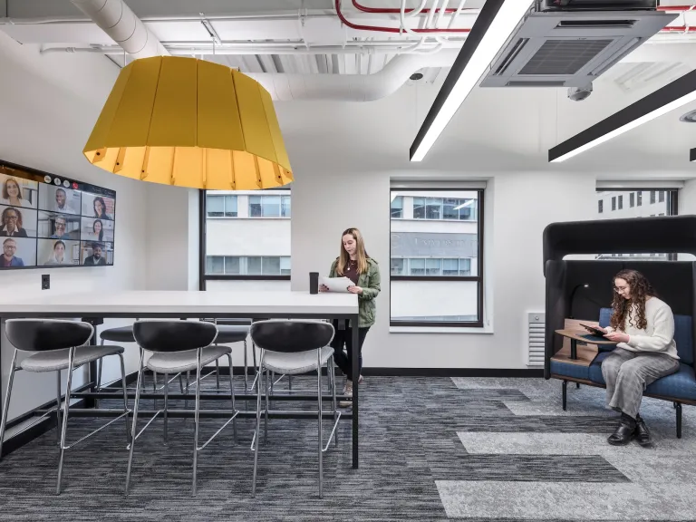 Internal of IT office conference space with TV featuring a Zoom call, tall table and accent chair