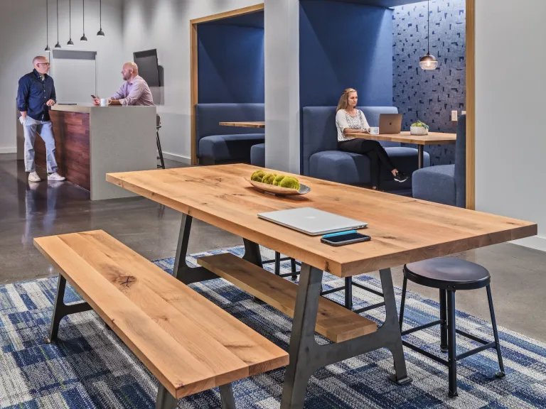 Close up of a picnic style table within a mixed use workspace, blue accented rug and walls