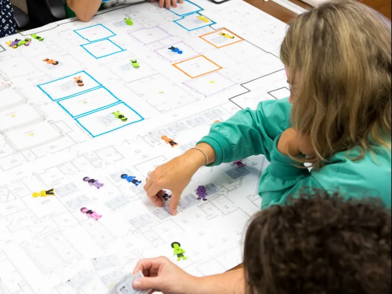 A planning session with clinical staff surround the blue prints a hospital