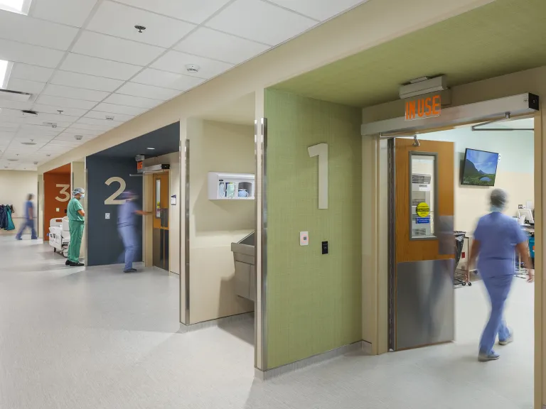 Doctors walking into separate rooms in a health facility.