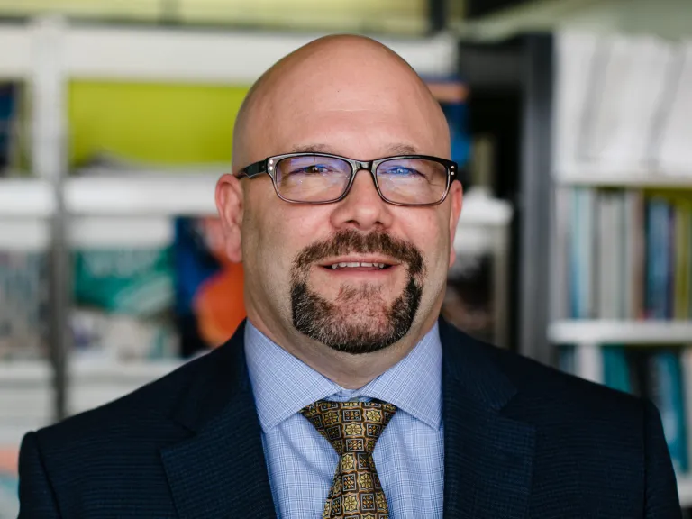 Tom Stanko smiling, wearing a navy blazer and blue shirt