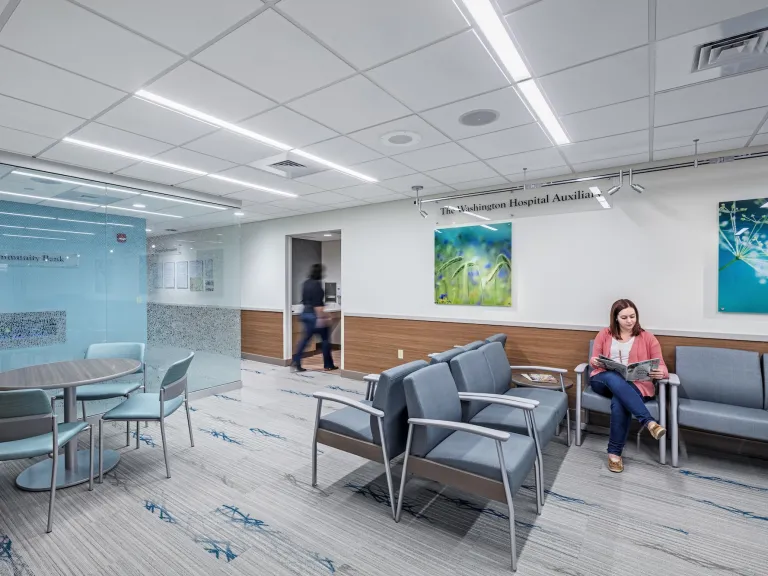 Waiting room of Care Center, featuring variety of cushioned blue chairs and blue green natural art on walls