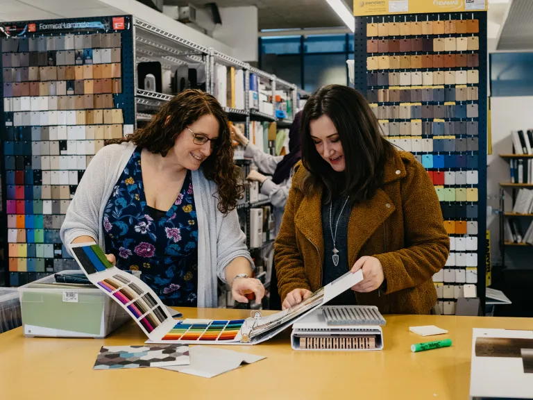 Two people looking through a swatch book.