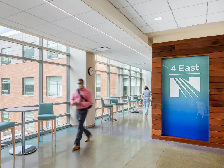 man walks through corridor with floor to ceiling windows