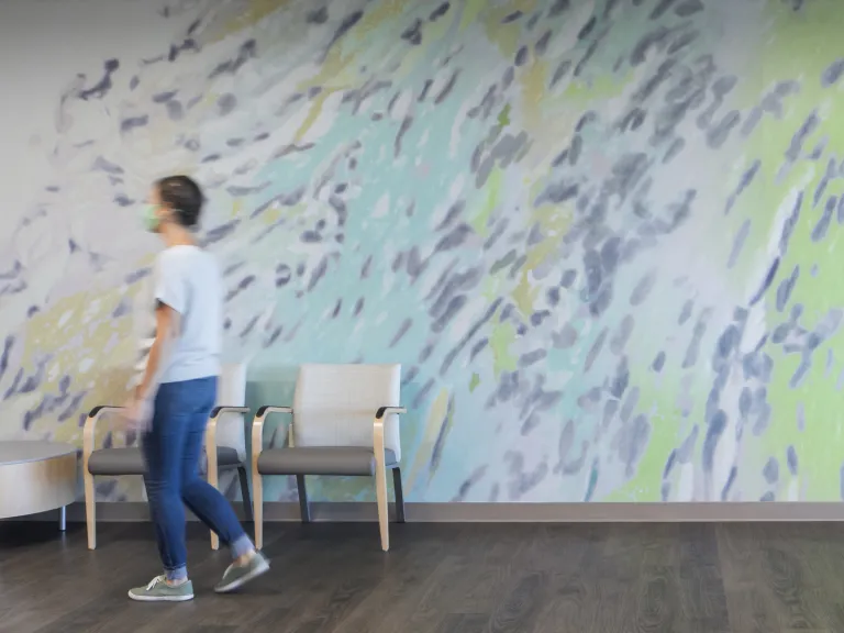 woman walks in front of wall mural