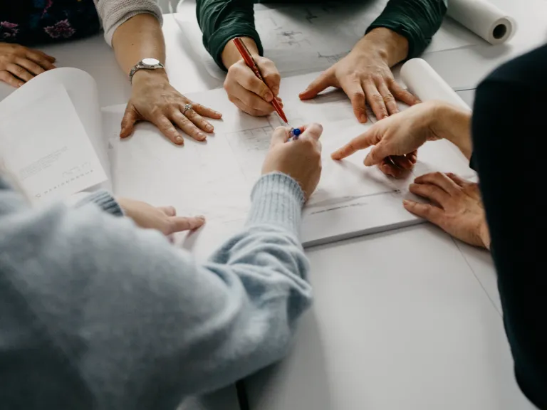 Set of hands with pens pointing and reviewing a document