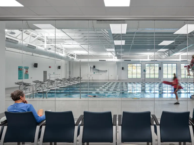 man viewing indoor pool through large window