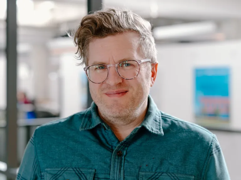 man with glasses wearing a teal shirt