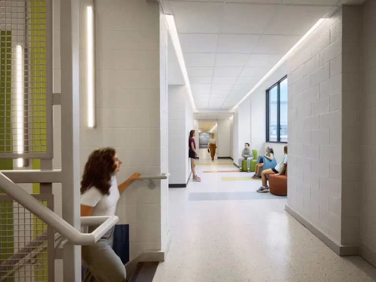 woman walking up stairs into hallway with children in colorful chairs