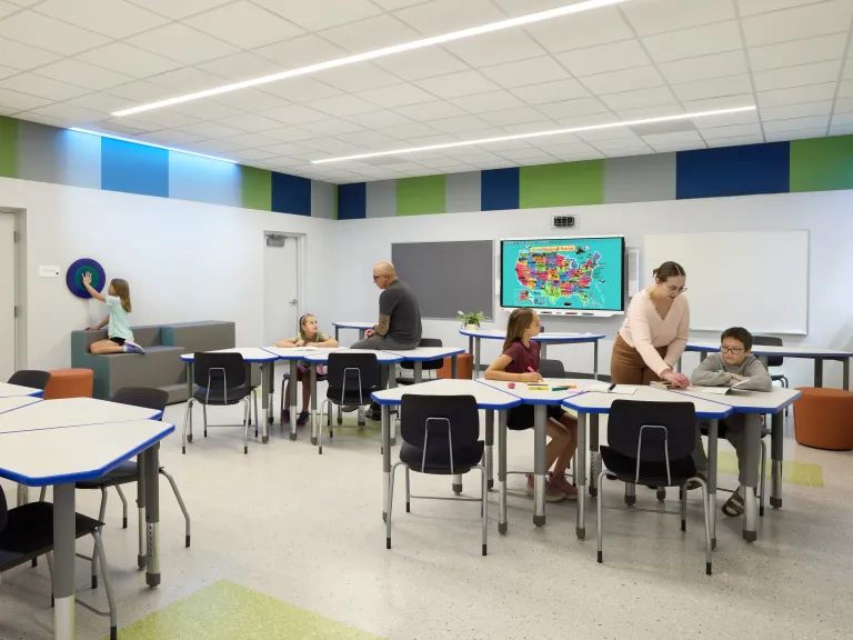 students working at grouped tables in classroom with green and blue accents