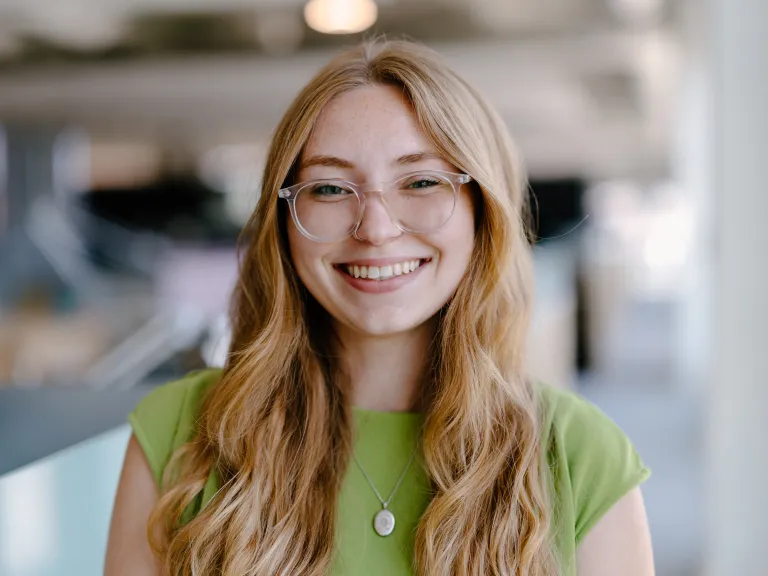 woman with long wavy hair wearing glasses and green shirt