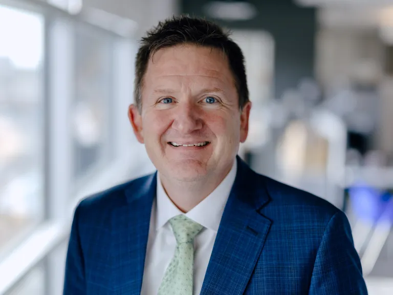smiling man in blue sports coat and pale green tie