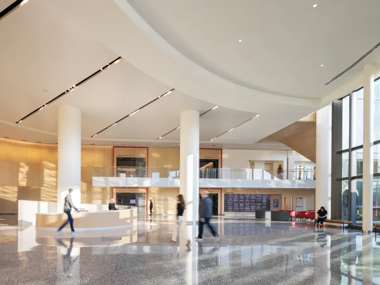 atrium lobby with circular reception desk, curved ceiling, floor-to-ceiling windows, and modern wood panelling 