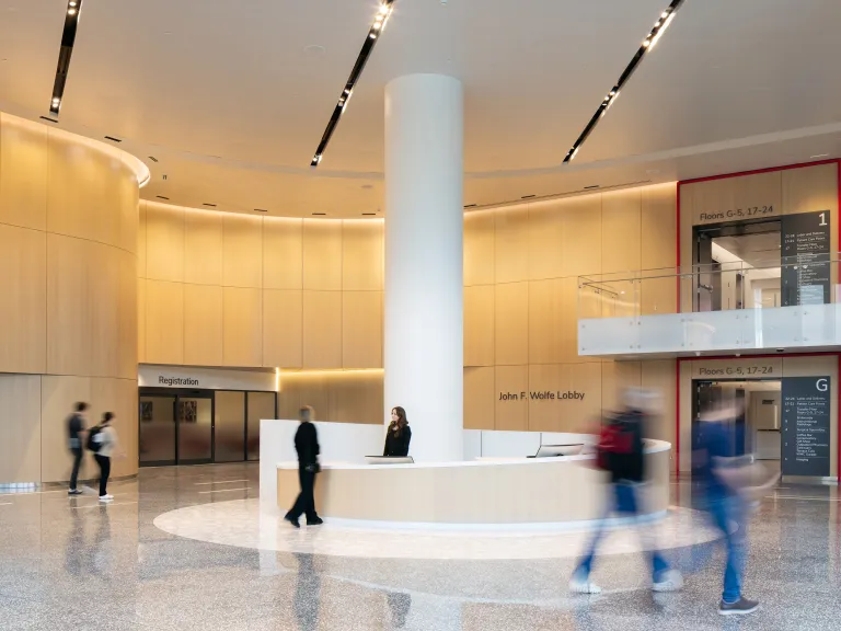 hospital visitors walking through lobby with circular reception desk and curved wood paneled walls